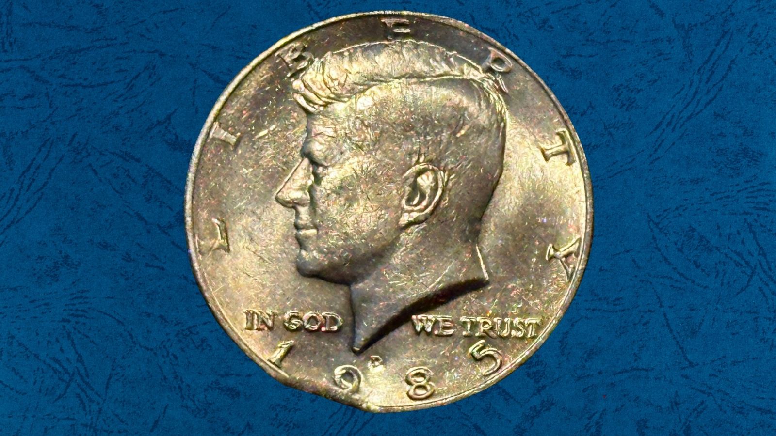 1985 Kennedy Half Dollar clipped planchet error showing a smooth crescent-shaped void along the rim edge