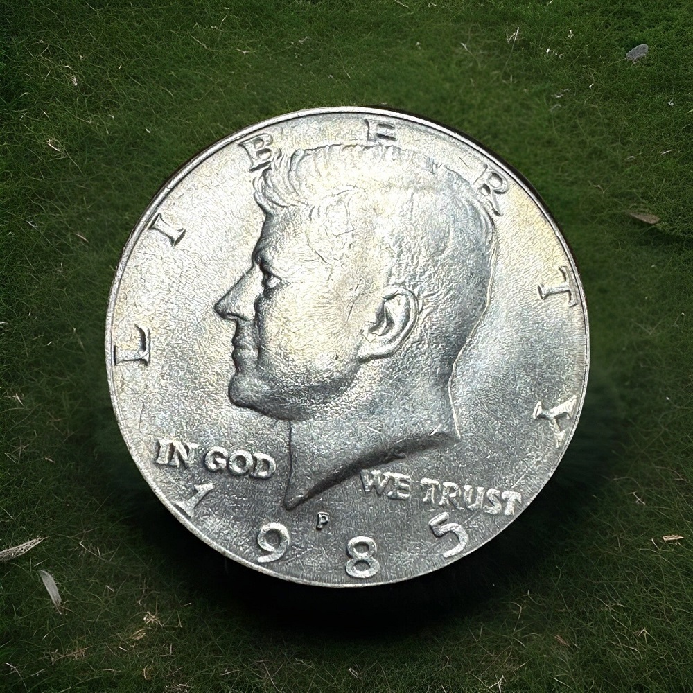 1985 Kennedy Half Dollar broadstrike error showing oversized coin without reeded edge, or die crack showing raised line across the design